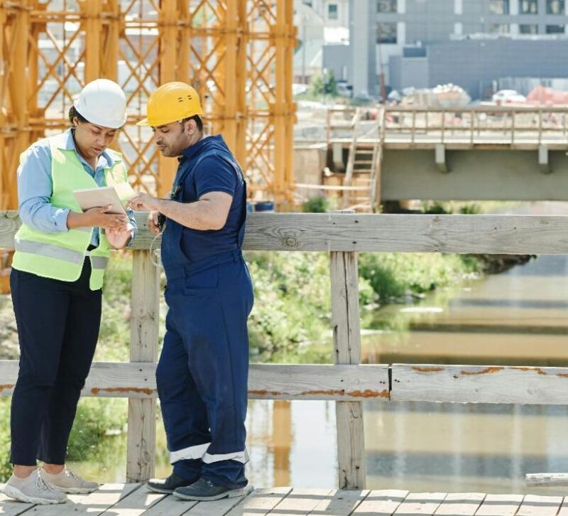 Construction professionals reviewing project data on-site using unified vendor management software.