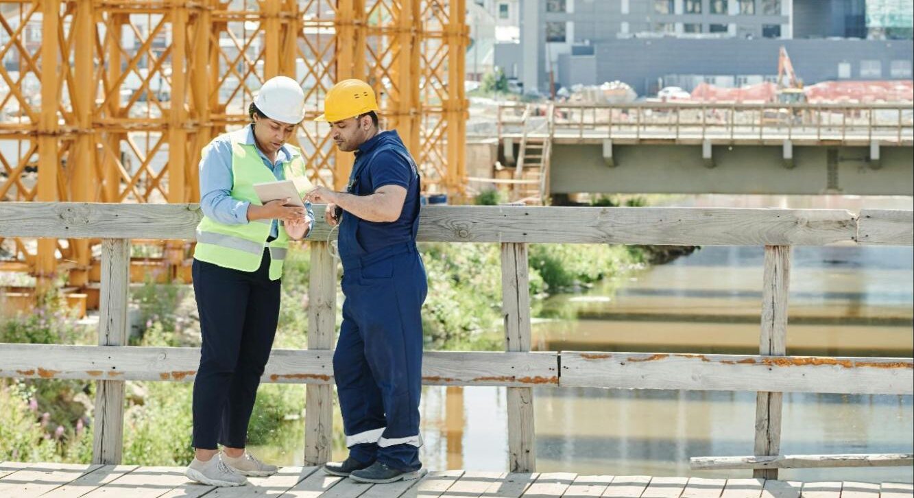 Construction professionals reviewing project data on-site using unified vendor management software.