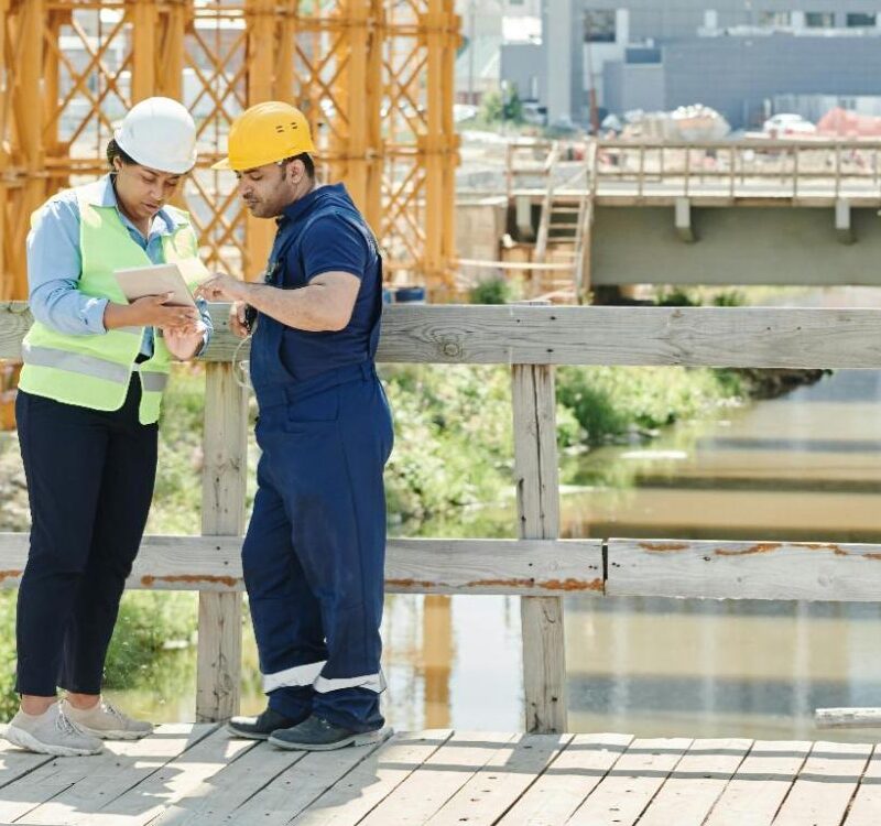 Construction professionals reviewing project data on-site using unified vendor management software.