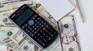 Calculator and cash illustrating hidden cost buildup from delayed construction accounting services over time.