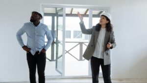 Two construction professionals reviewing an interior space while discussing project details and site conditions.