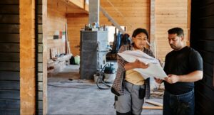Construction team reviewing printed drawings inside an unfinished home during active project coordination.