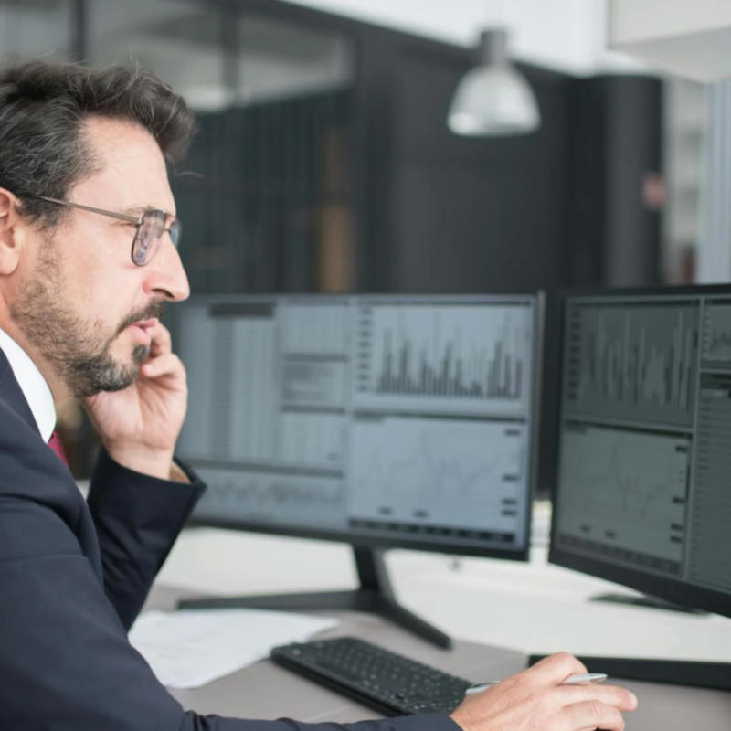 CFO reviewing financial data on dual monitors using construction ERP software to track real-time project costs and performance